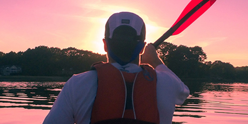 Individual paddling down the Jame's River in a kayak at sunset. 
